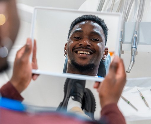 Man smiling at reflection in handheld mirror