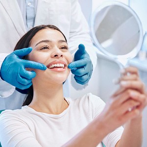 Patient smiling at reflection in handheld mirror