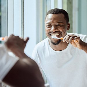 Man smiling while brushing his teeth