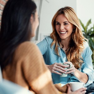 Woman smiling while drinking coffee with friend