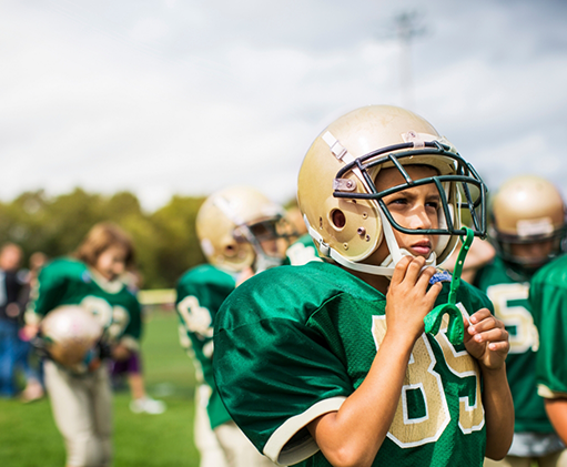 Football player with athletic mouthguard attached to their helmet
