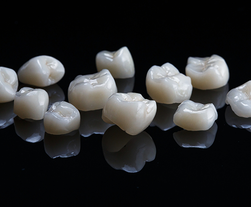 Several white dental crowns against a black background