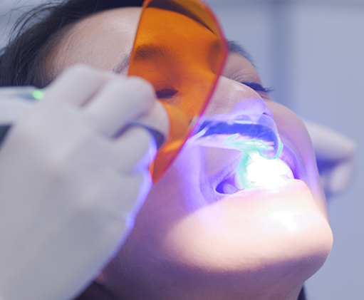 Dental patient having an ultraviolet light applied to her tooth