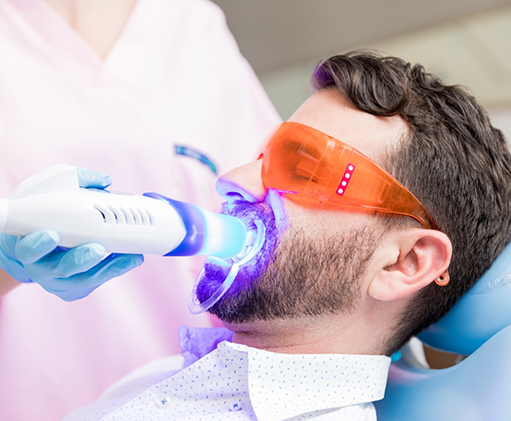 Man in the dental chair having a teeth whitening light shone onto his teeth