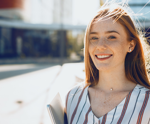 Young woman with long red hair smiling in the sun