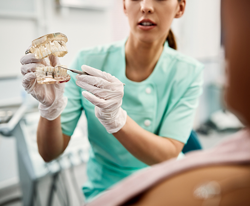 Dentist showing a model of a dental implant to a patient