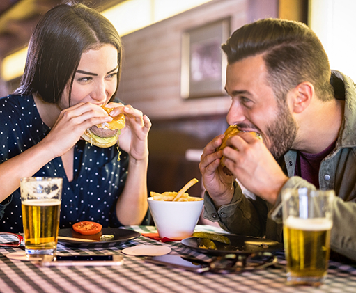 Man and woman eating burgers at a restaurant