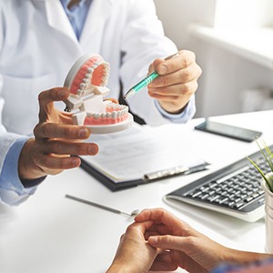 Dentist pointing to model of teeth in office