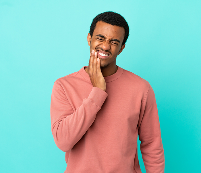 Man holding his cheek in pain needing an emergency dentist in Justin