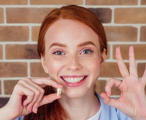 A woman holding an extracted tooth