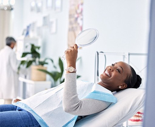 Woman smiling at reflection in handheld mirror