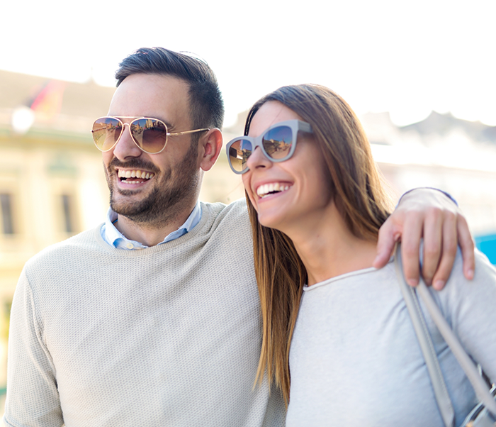 Young man and woman in sunglasses smiling outdoors after gum disease treatment in Justin