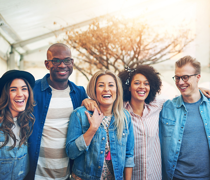 Group of adults smiling together outdoors after replacing missing teeth in Justin