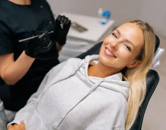 Blonde woman smiling in the dental chair after receiving dental services in Justin