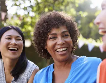 Three women laughing together outdoors