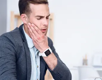 Man wincing in pain and holding the side of his jaw
