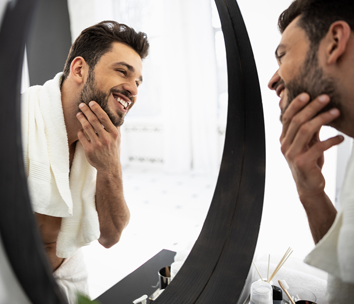 Man looking at his smile in a mirror after restorative dentistry treatment in Justin