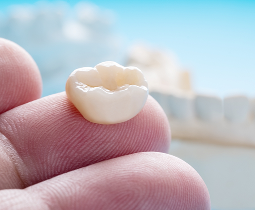 Close up of a dental crown resting on a finger