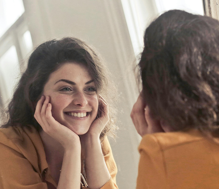 Woman looking closely at her flawless smile in a mirror