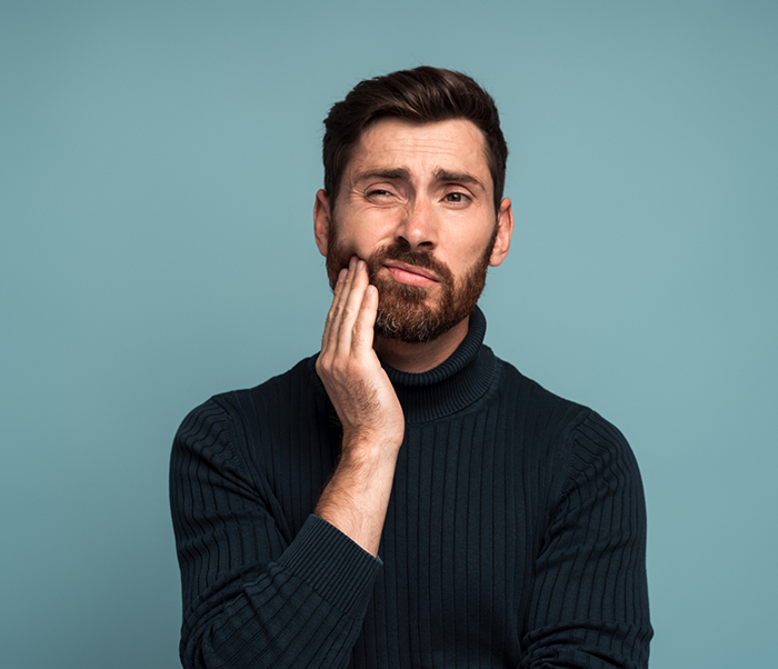Man holding the side of his jaw in pain before T M J treatment in Justin