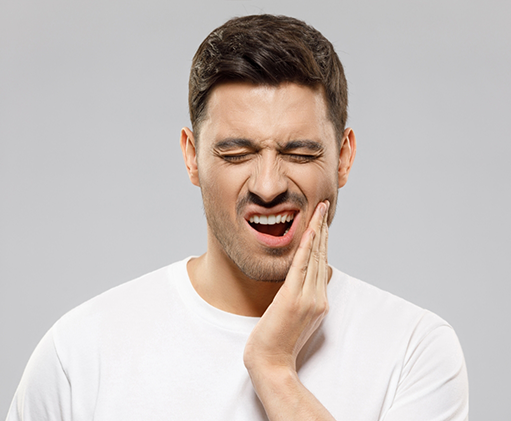 Man holding the side of his jaw and wincing in pain