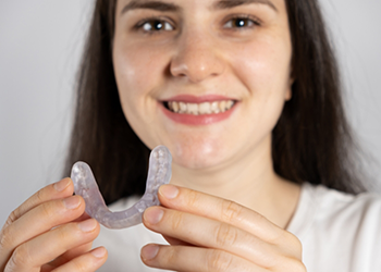 Smiling woman holding an occlusal splint tray near her teeth