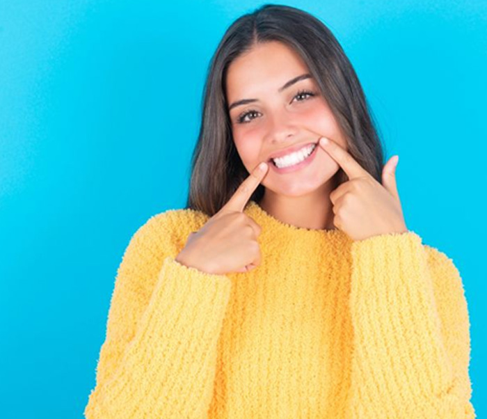 Woman pointing at her beautiful, bright smile