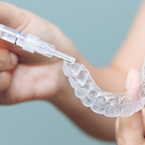 Person placing whitening gel inside whitening tray