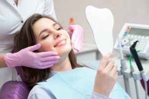 Woman smiling into mirror in dentist's chair.